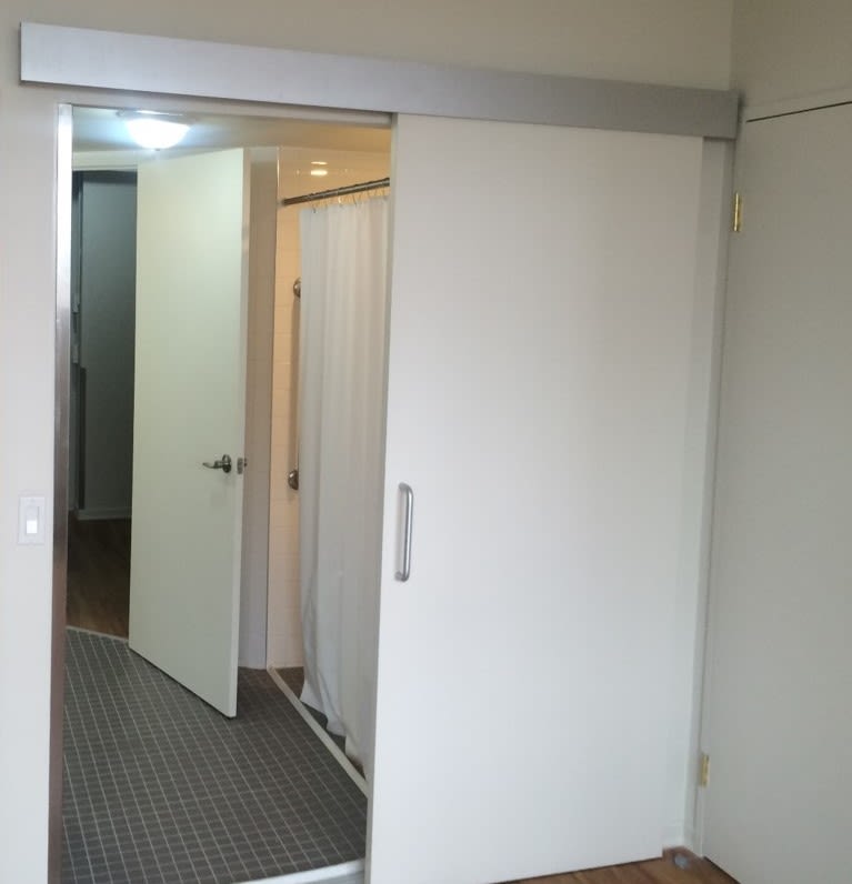 The inside of an apartment with a sliding door and extra wide doorway.