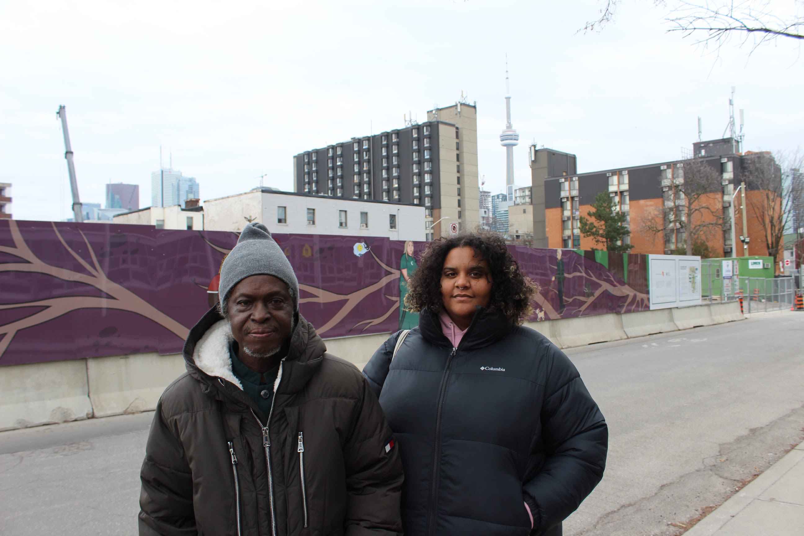 photo of two alexandra park residents in front of hoarding mural on dundas