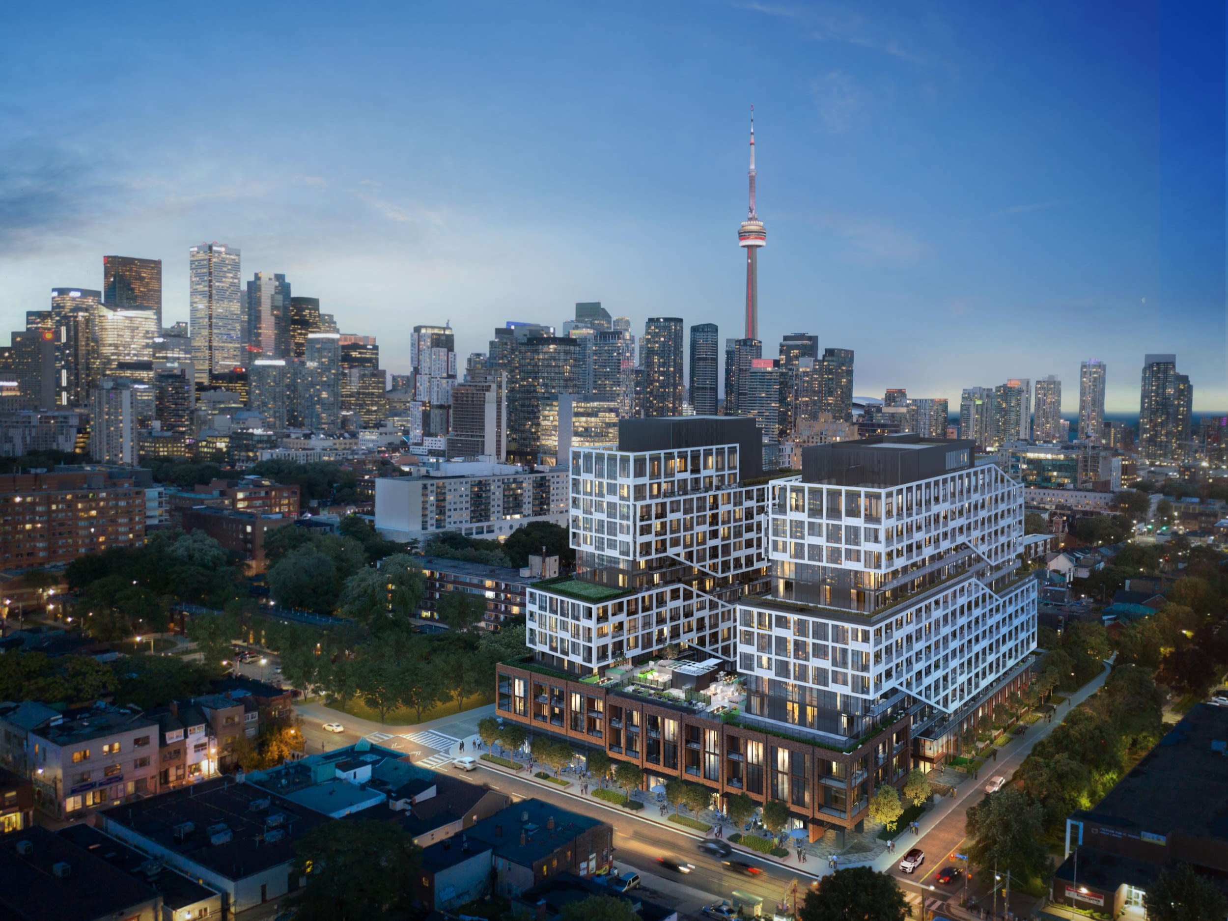 A wide-angle view at dusk of a condo building in the heart of Toronto. The CN Tower and other high-rise buildings can be seen in the background.