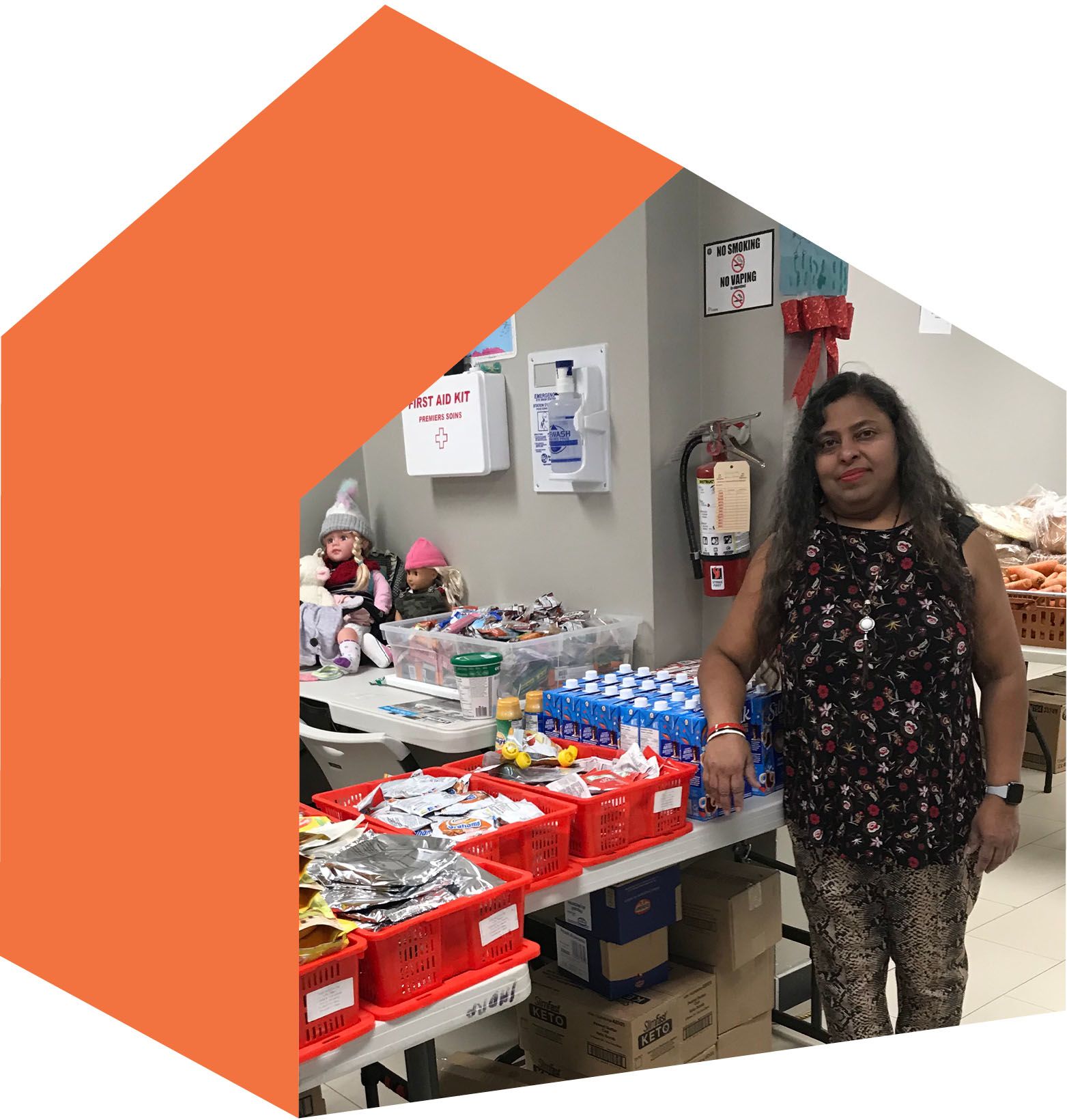 Indra Adjei standing in front of tables full of donated food.