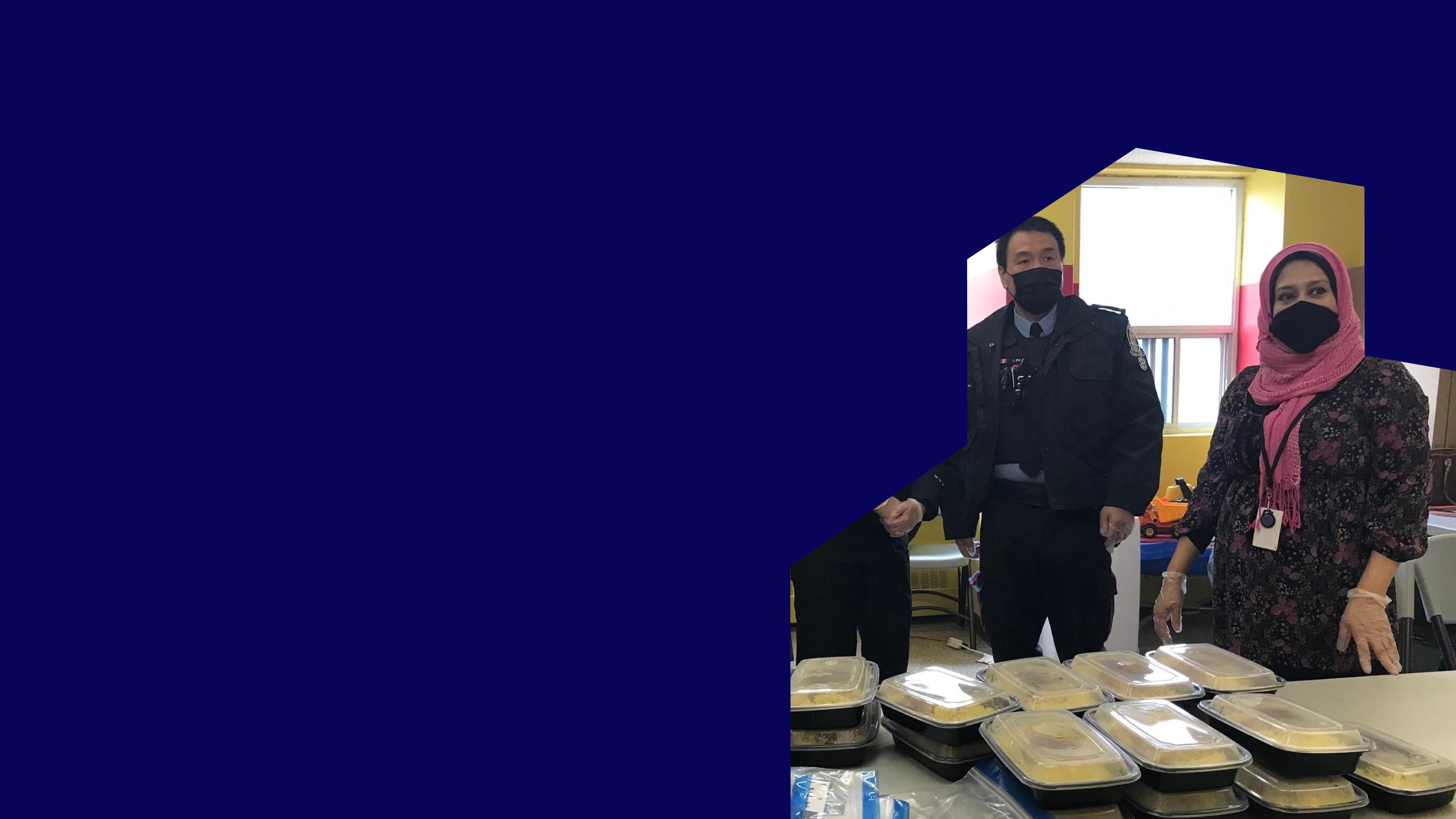TCHC staff and special constables wearing face masks standing behind a table with packaged meals.