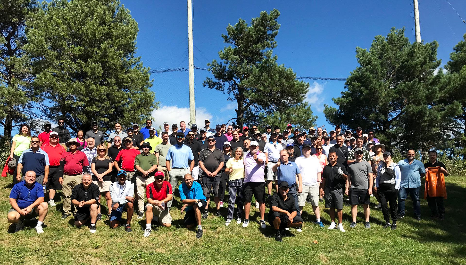 Large group of people posing outdoors in the sunshine