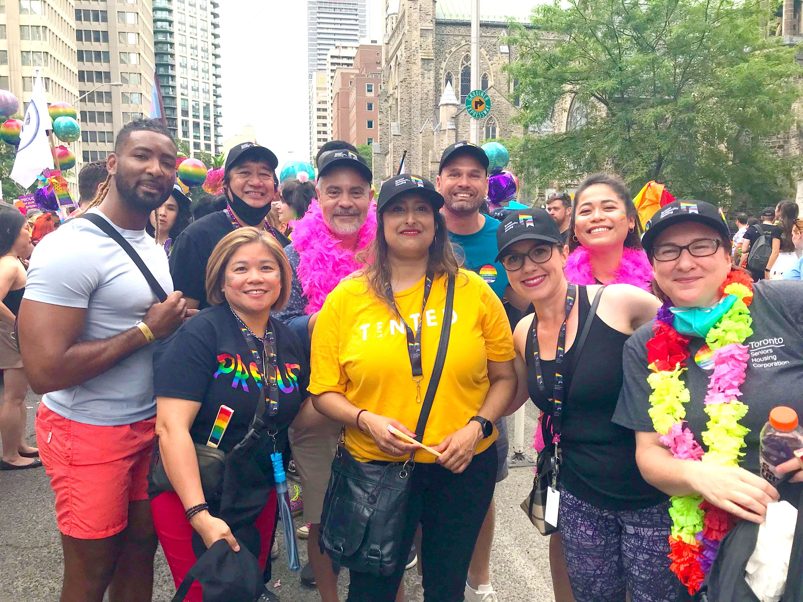Group of people posing outside, wearing Pride colour