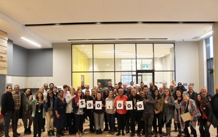 Photo of a large group of people holding up a banner that says "$90,000"