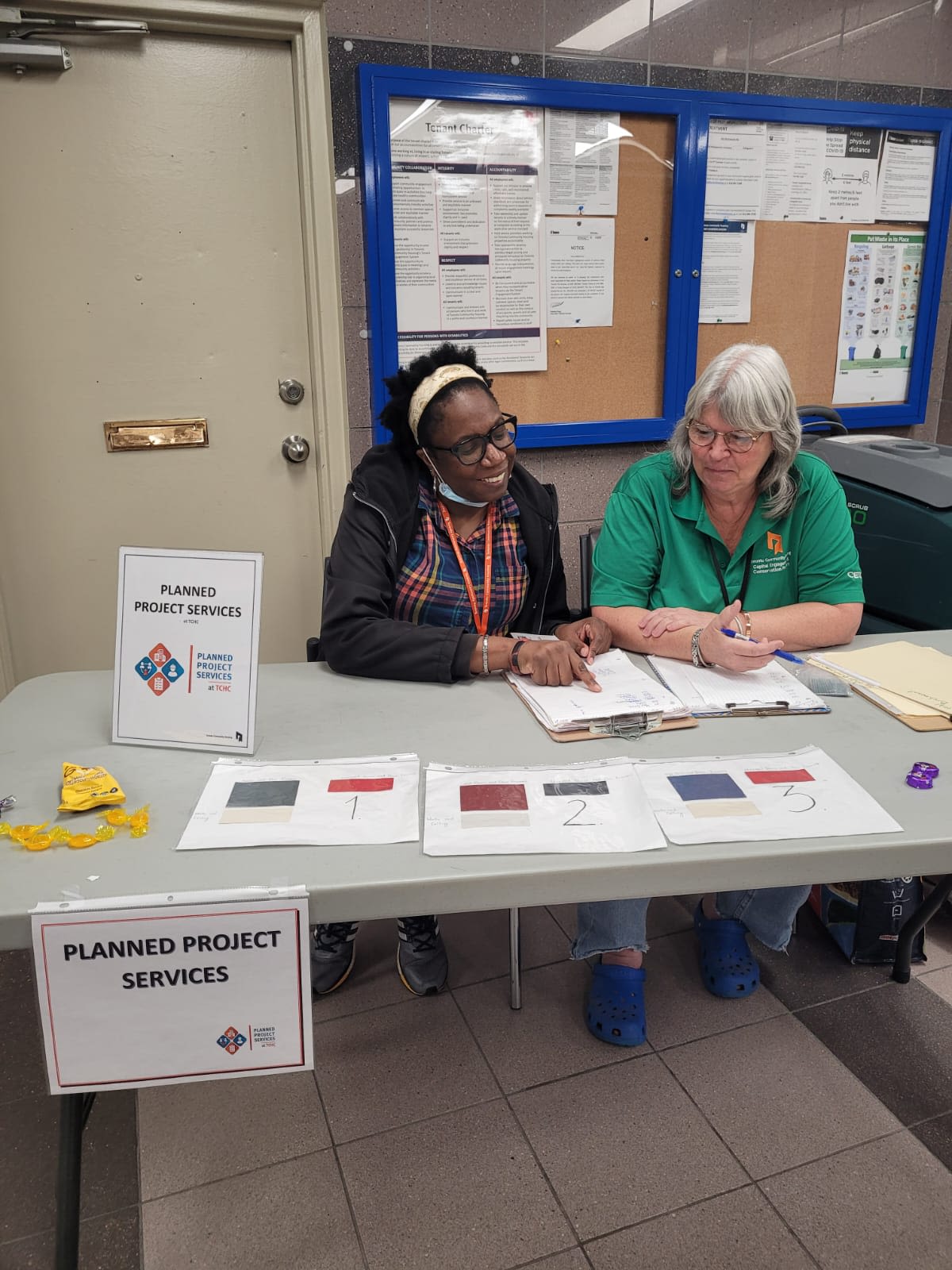 Photo of two people sat at a table with clipboards