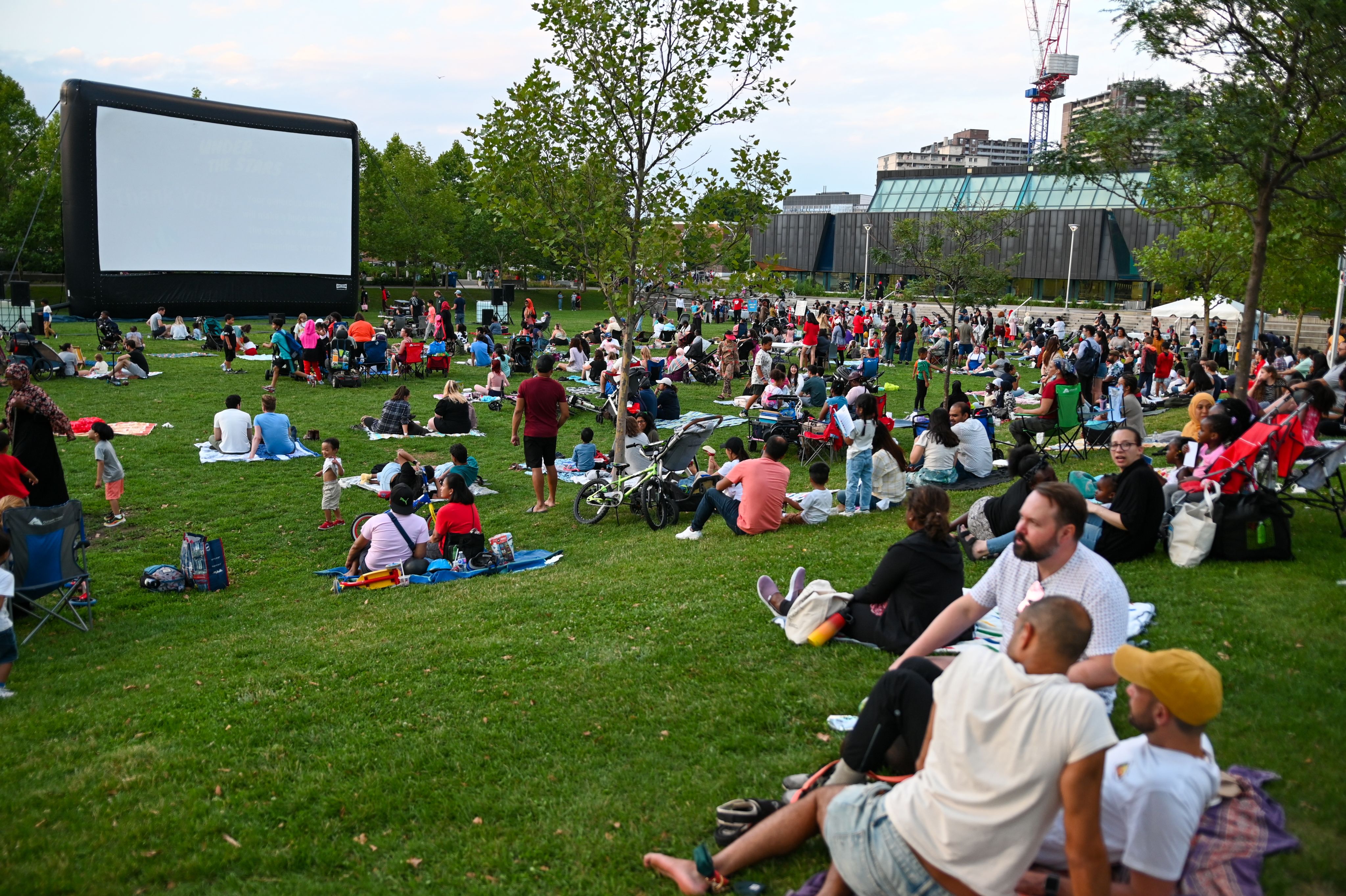 People sitting in the park watching a movie screen