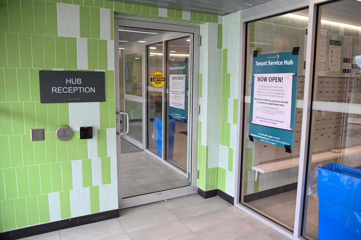 Entrance of a Tenant Service Hub. There are signs on the walls that read 'Hub Reception' and 'Now Open'