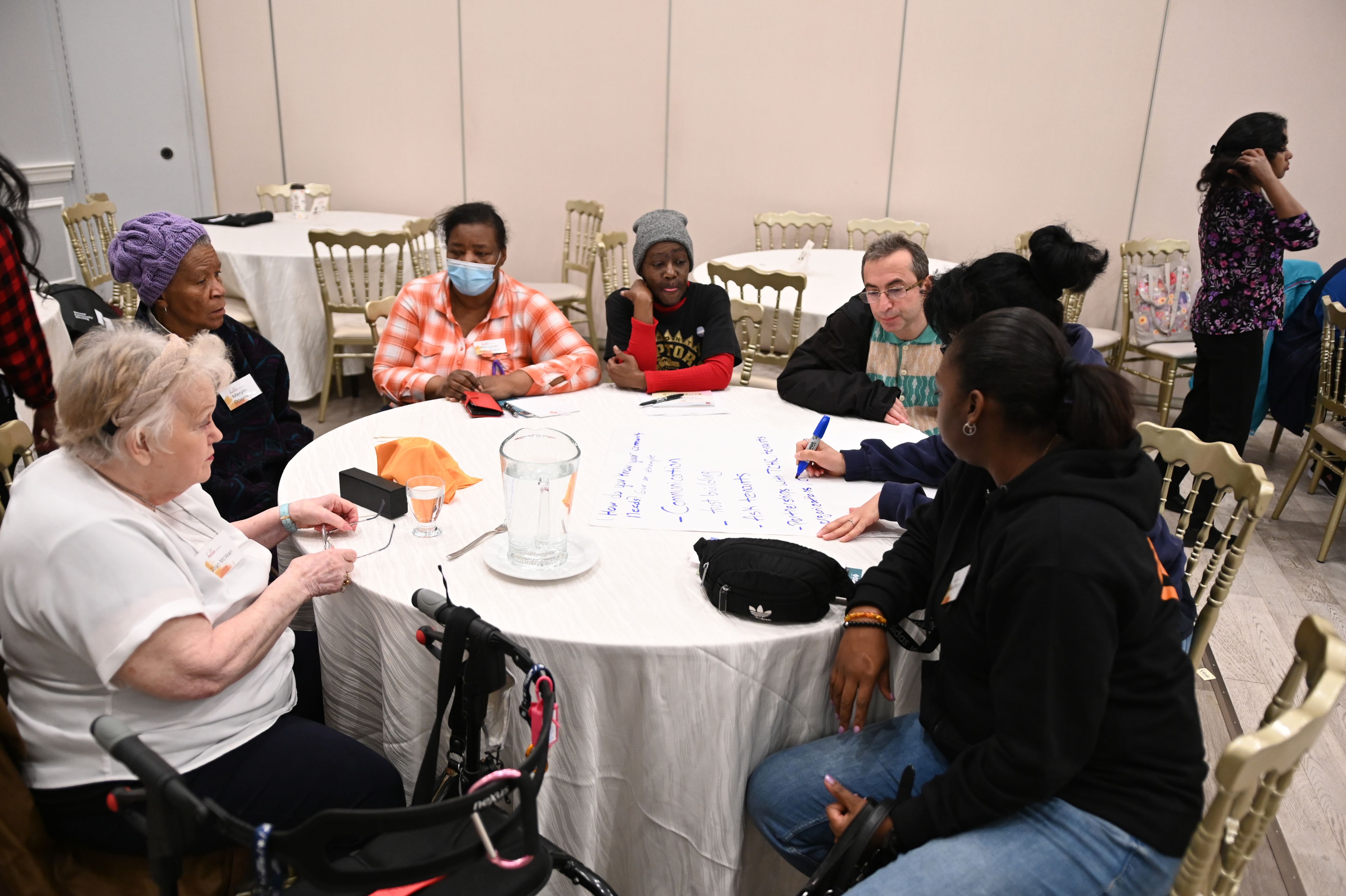 Tenants and staff sitting around a table in discussion. One person is taking notes.