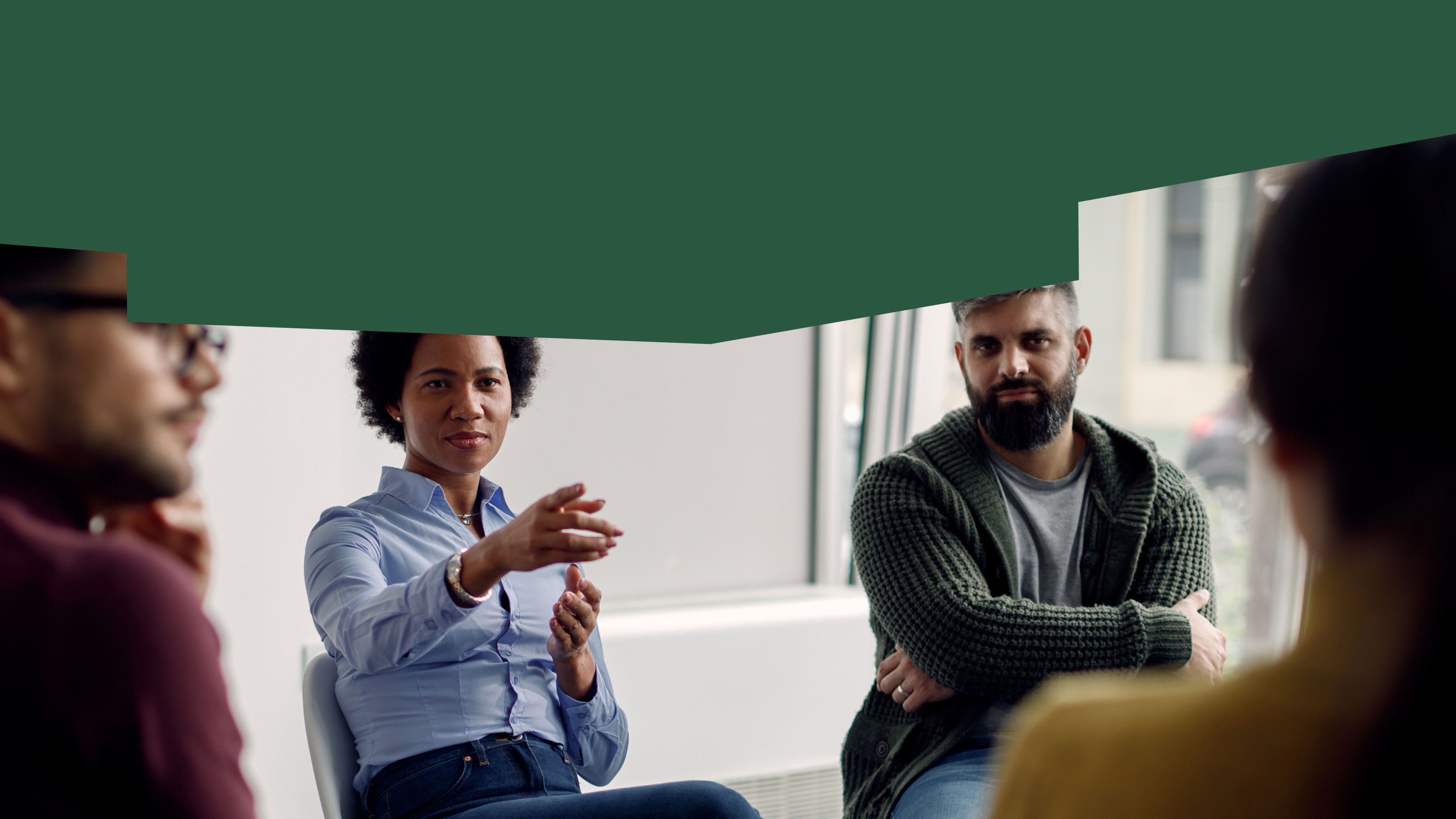 A group of people are sitting in a circle, one of them is pointing to something.