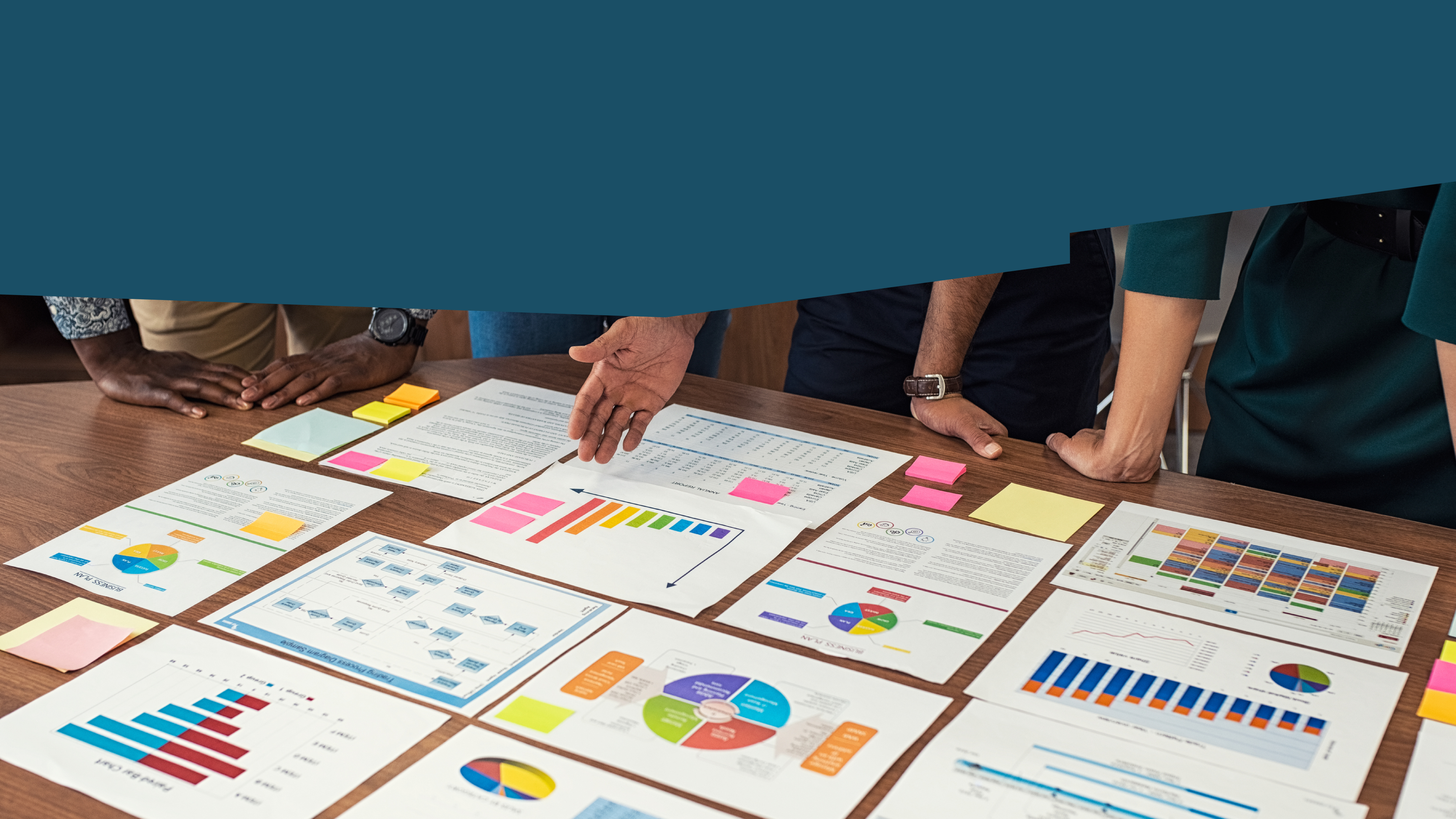 A group of people gathered around a table with printouts of charts and graphs.