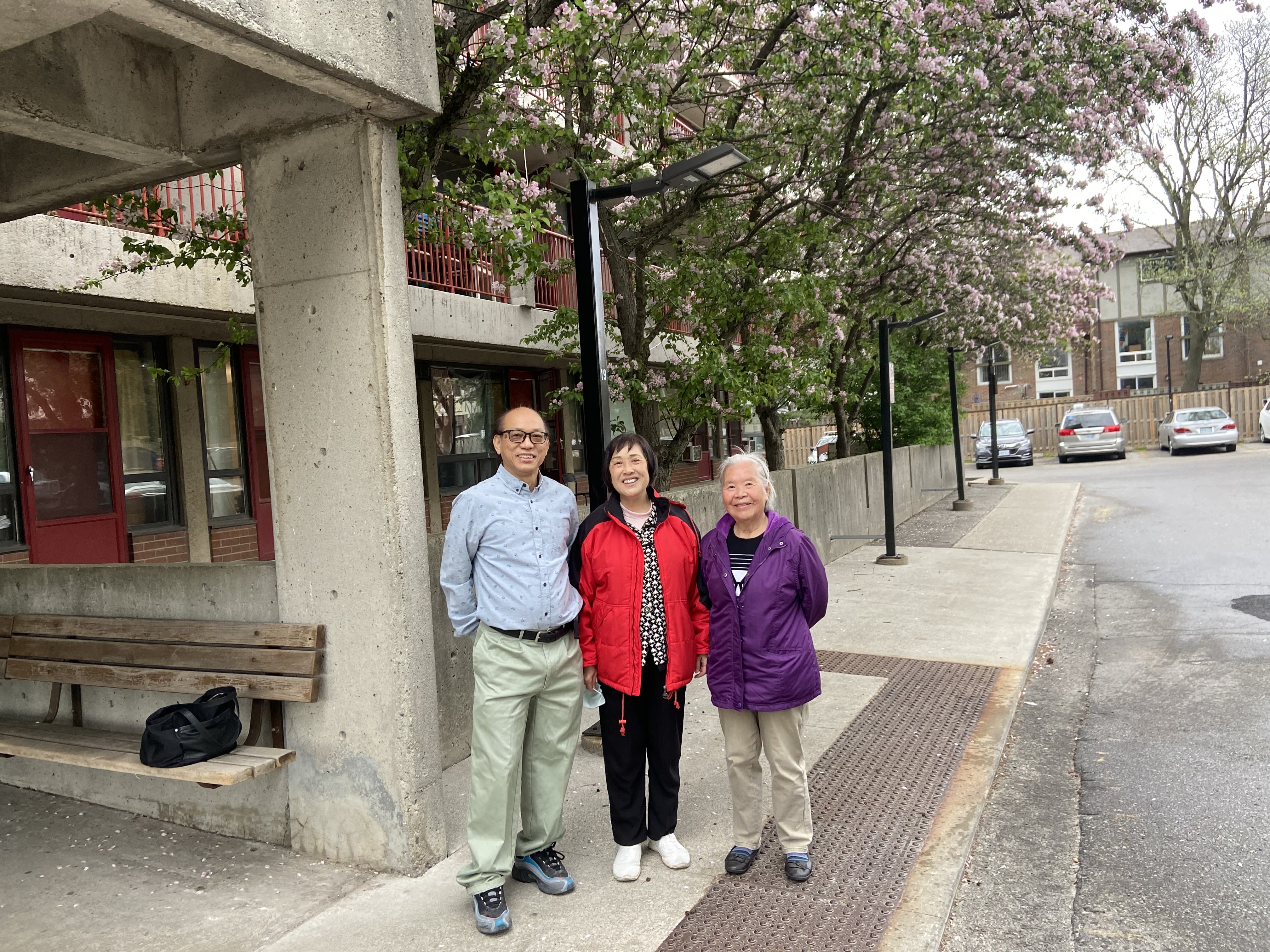 photo of three senior tenants standing on the sidewalk outside their building