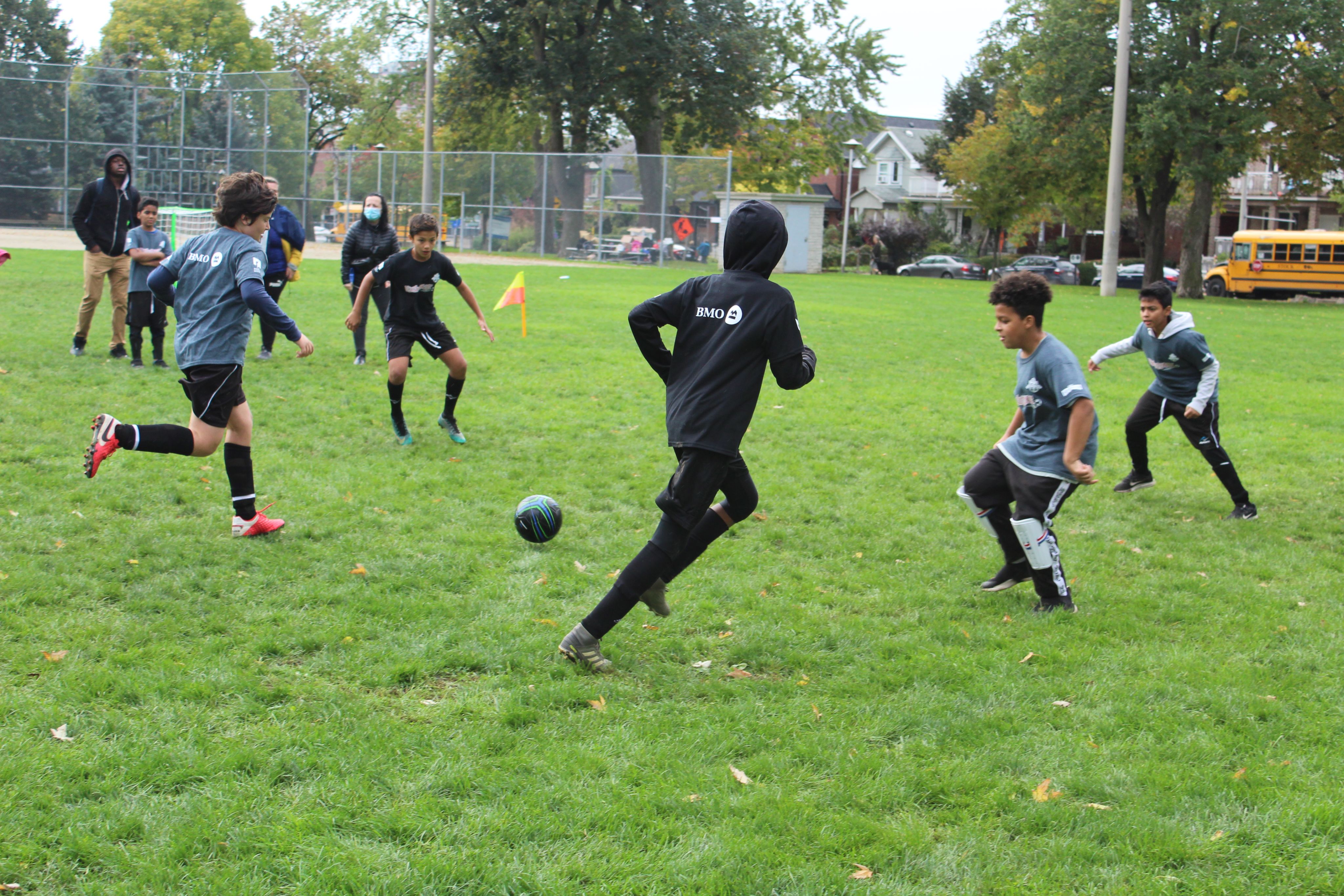 A group of children playing soccer in a grassy field.