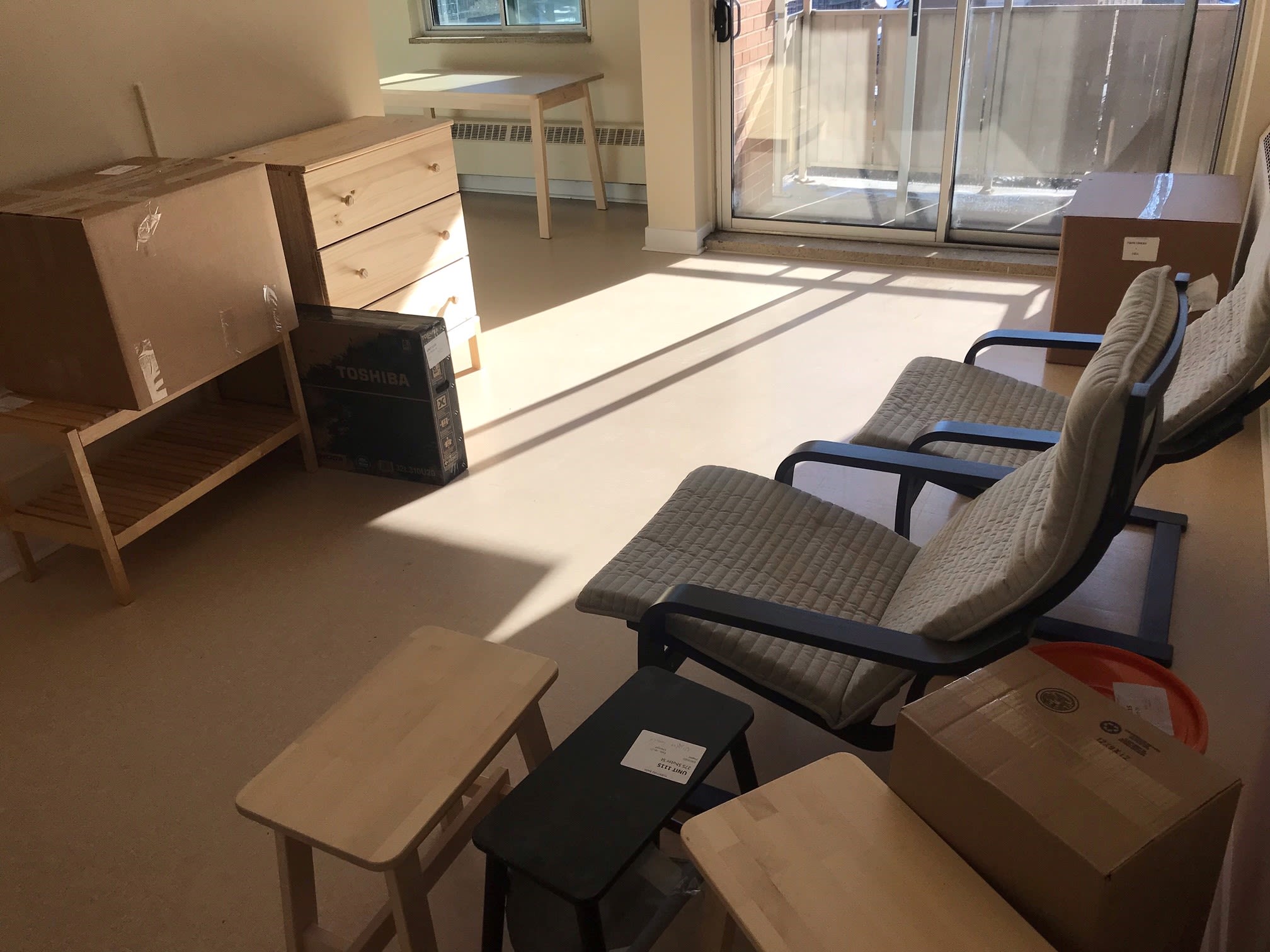An empty apartment with glass sliding doors, assorted wood furniture.