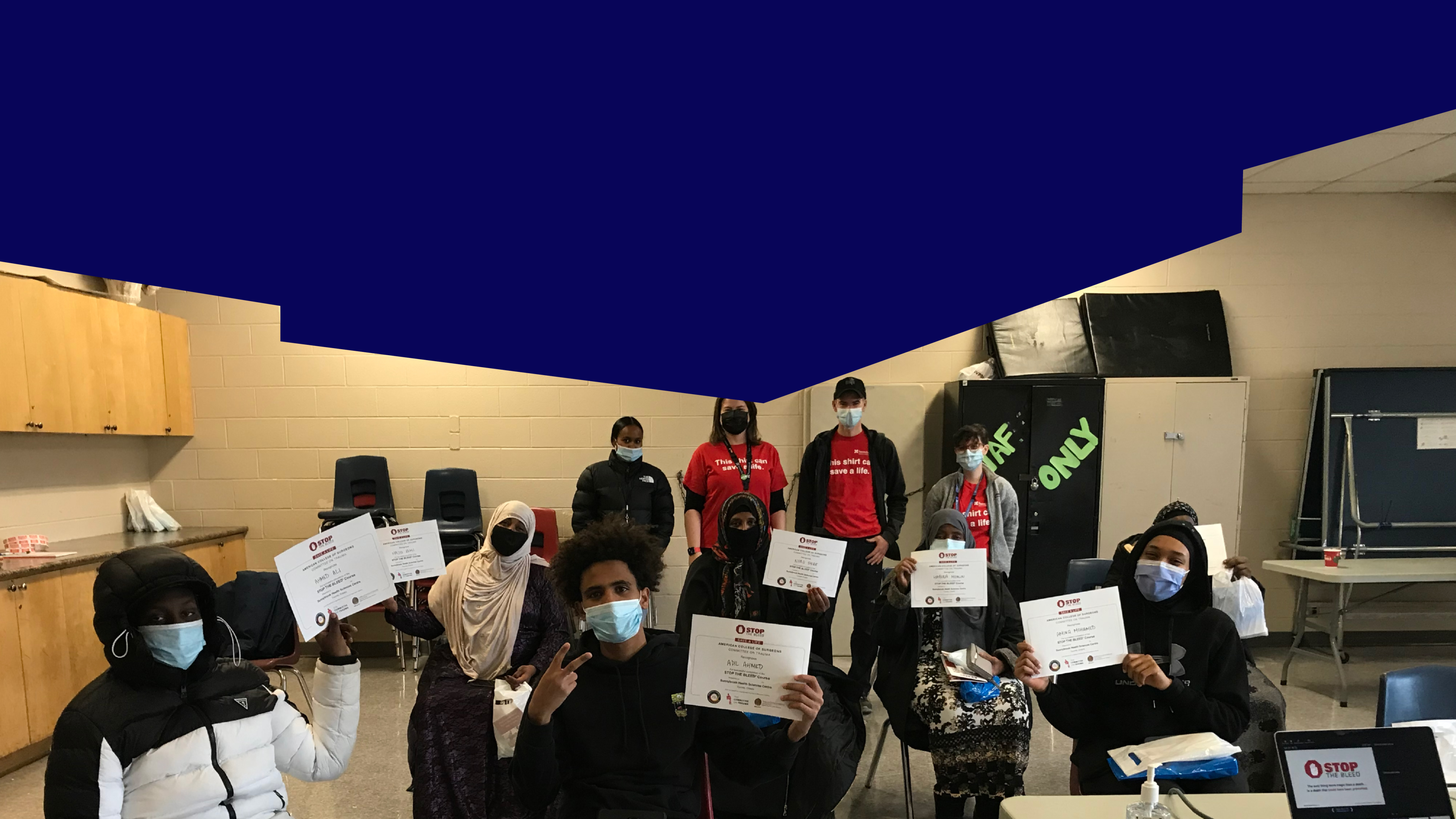 A group of youth in face masks holding up certificates. 