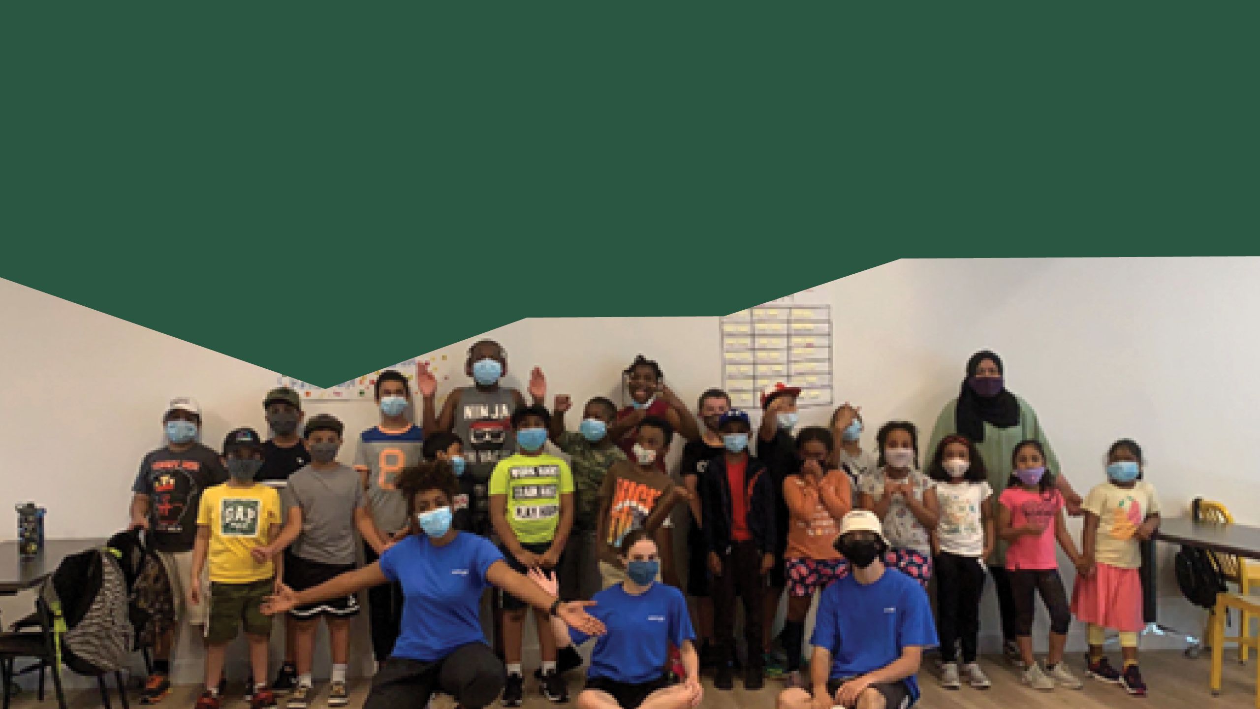 A group of children wearing face masks standing with Rookie League staff.