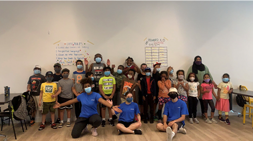 A group of children wearing face masks standing with Rookie League staff.