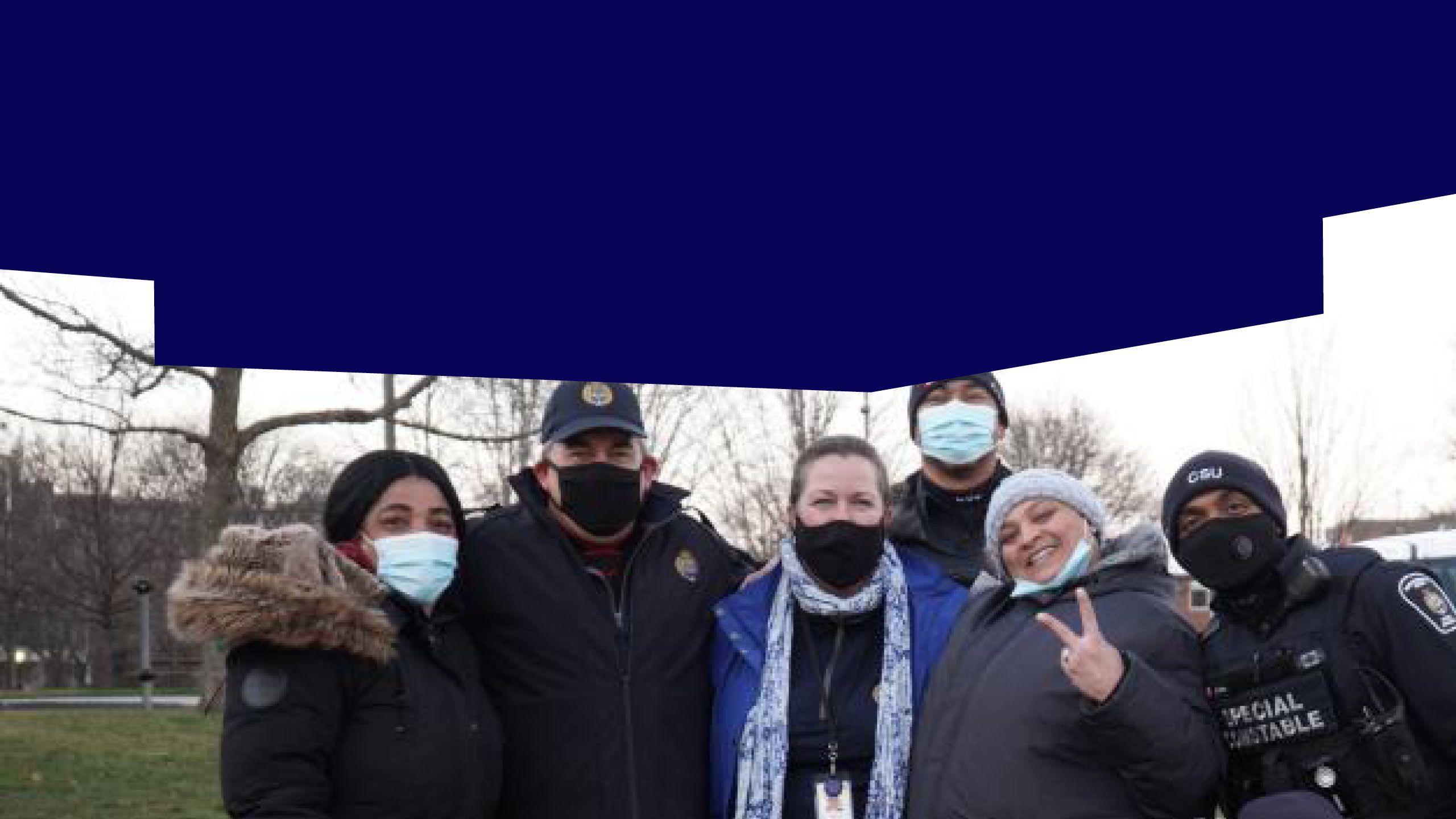 A group of people wearing face masks and winter clothing posing with a Special Constable outdoors.